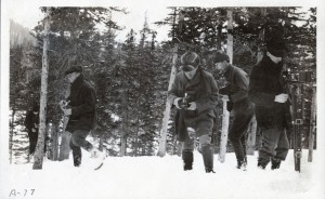 Five men stand in a snowy, mountainous landscape holding cameras.