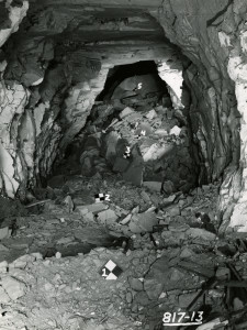 A black and white photograph depicts a pit with rubble in it. On the bottom right corner of the picture is white lettering that reads, "817-13."