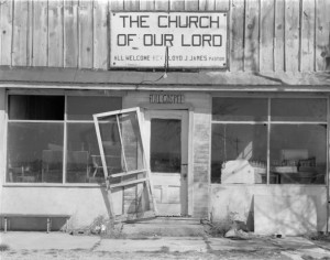 The derelict edifice of a building sports a sign that reads, "THE CHURCH OF OUR LORD ALL WELCOME REV LLOYD J JAMES PASTOR."