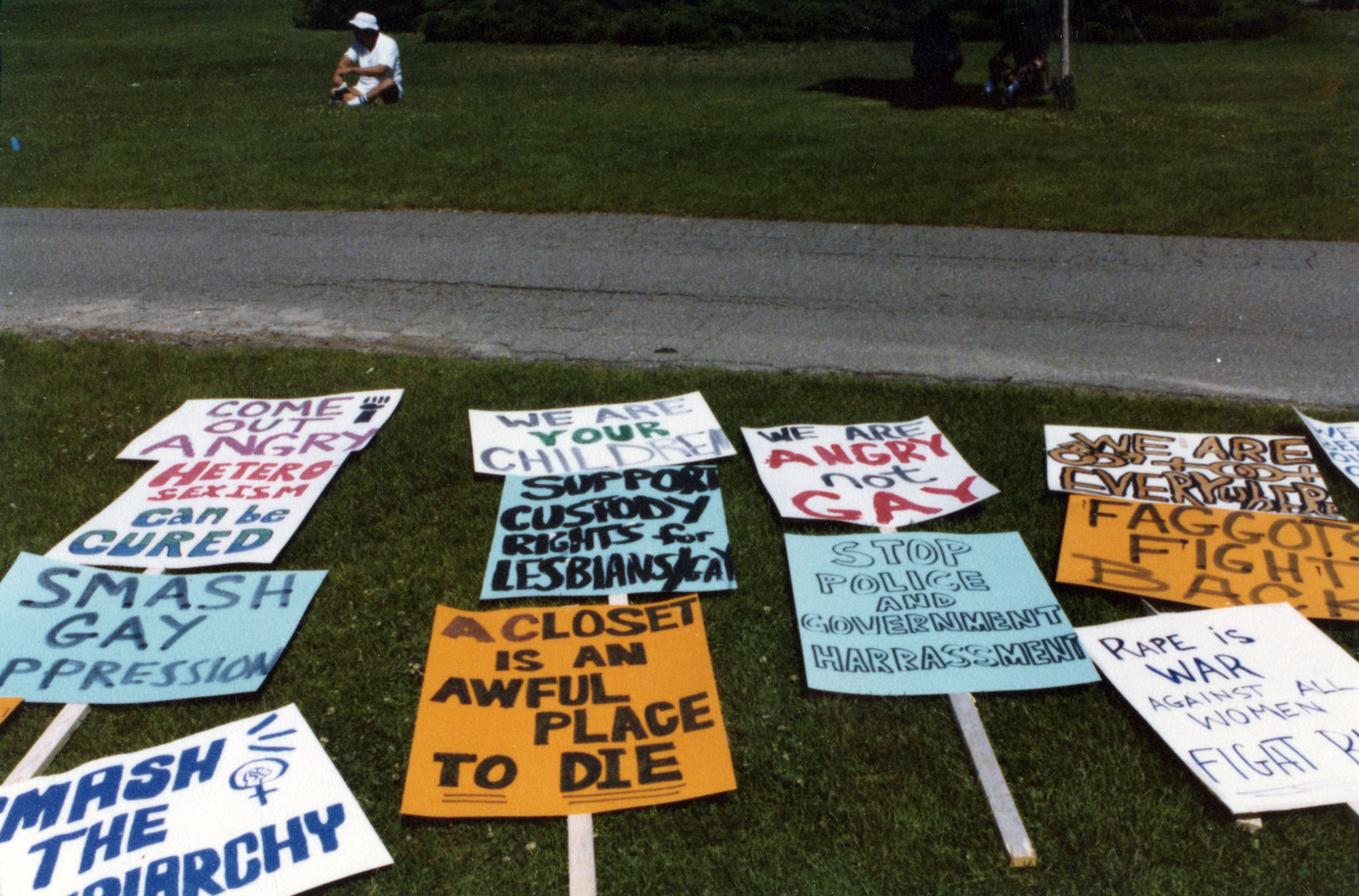A bevy of protest signs lay flat on a large swath of grass.