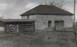 A black and white photo of the hipped roof barn and wood framed extension.
