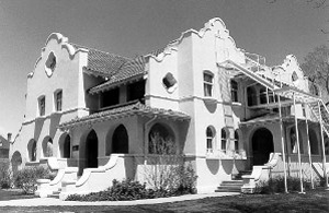 A black and white photo of the house with curvilinear gables, and prominent windows on top. On the bottom stand several arcades and some stairs on the right. 