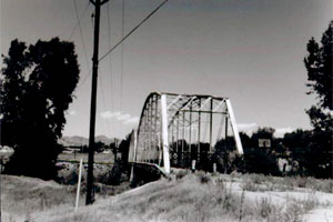 A picture of the bridge with truss from near the road side in black and white.