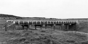 A black and white photo of the bridge with white railing. 