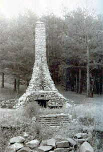  A black and white photo of a chimney surrounded by trees in the park. 