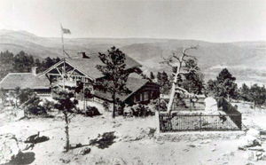 A black and white photo of a building overlooking the mountains. 
