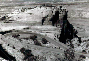 A black and white photo of a road looping in a series of rock structures