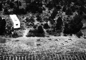 A black and white photo of the property with white trailer on the left in the distance. 