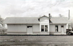 A view of the depot in black and white with pitched roof and cross gable on the right. 