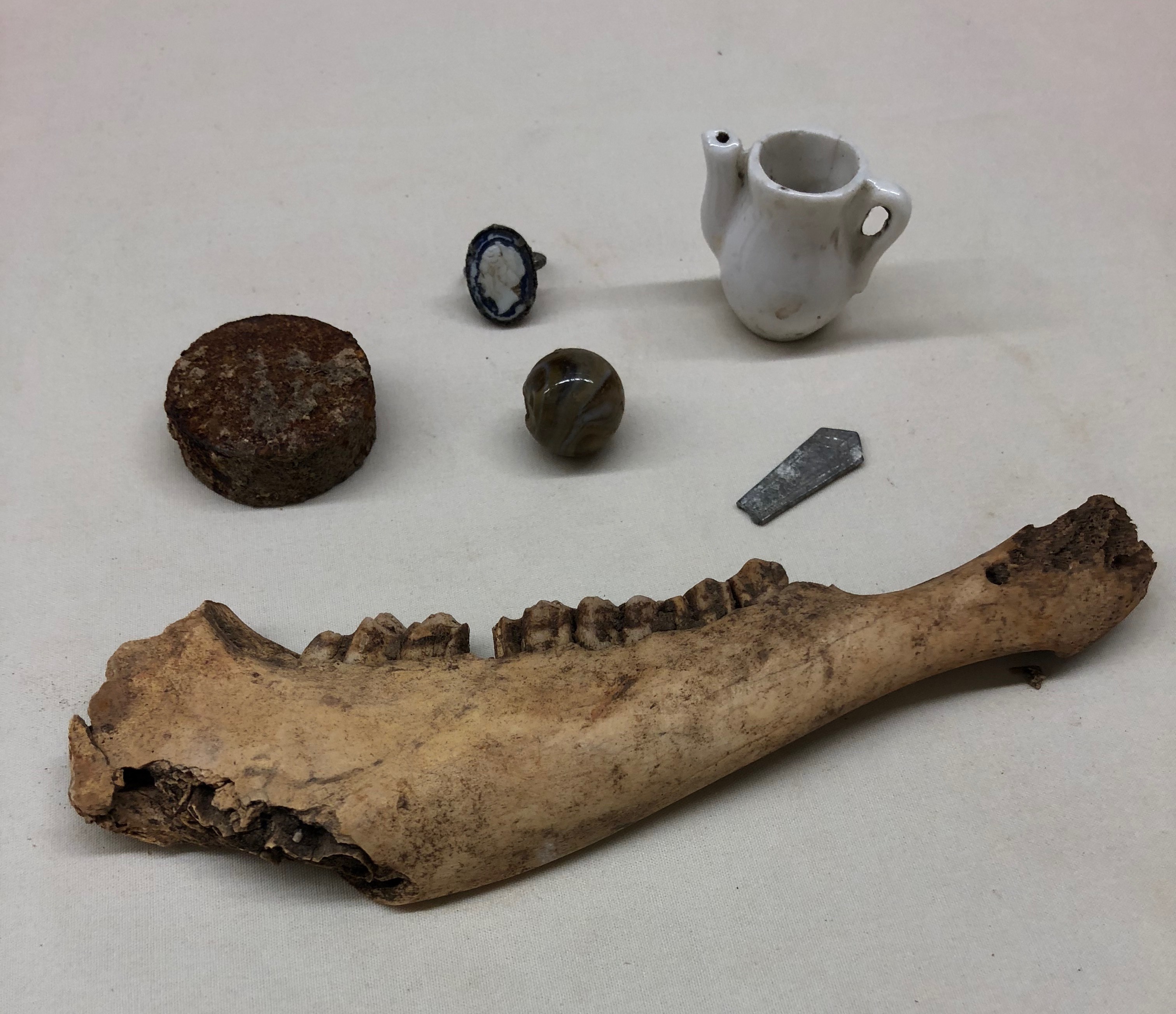 Archaeological items including jaw bone, ceramic pitcher, glass marble and more