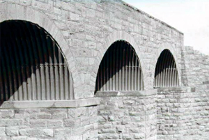 A black and white photo of the bridge from the bottom with brick abutments. 
