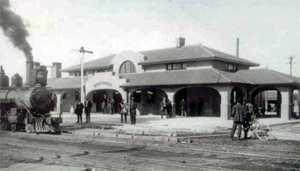 A black and white photo of the depot with pillars on bottom and two hipped roofs, one section above the other.