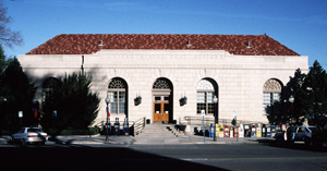 A view of the post office with hipped red roof white brick walls and arched entrance and windows.