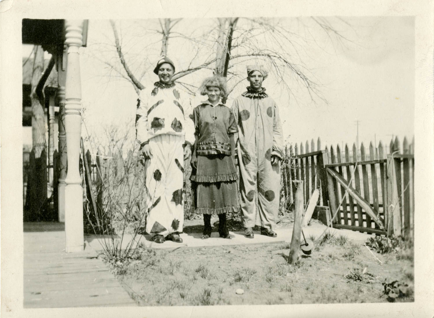 Three individuals dressed as clowns in a vintage Halloween photograph.
