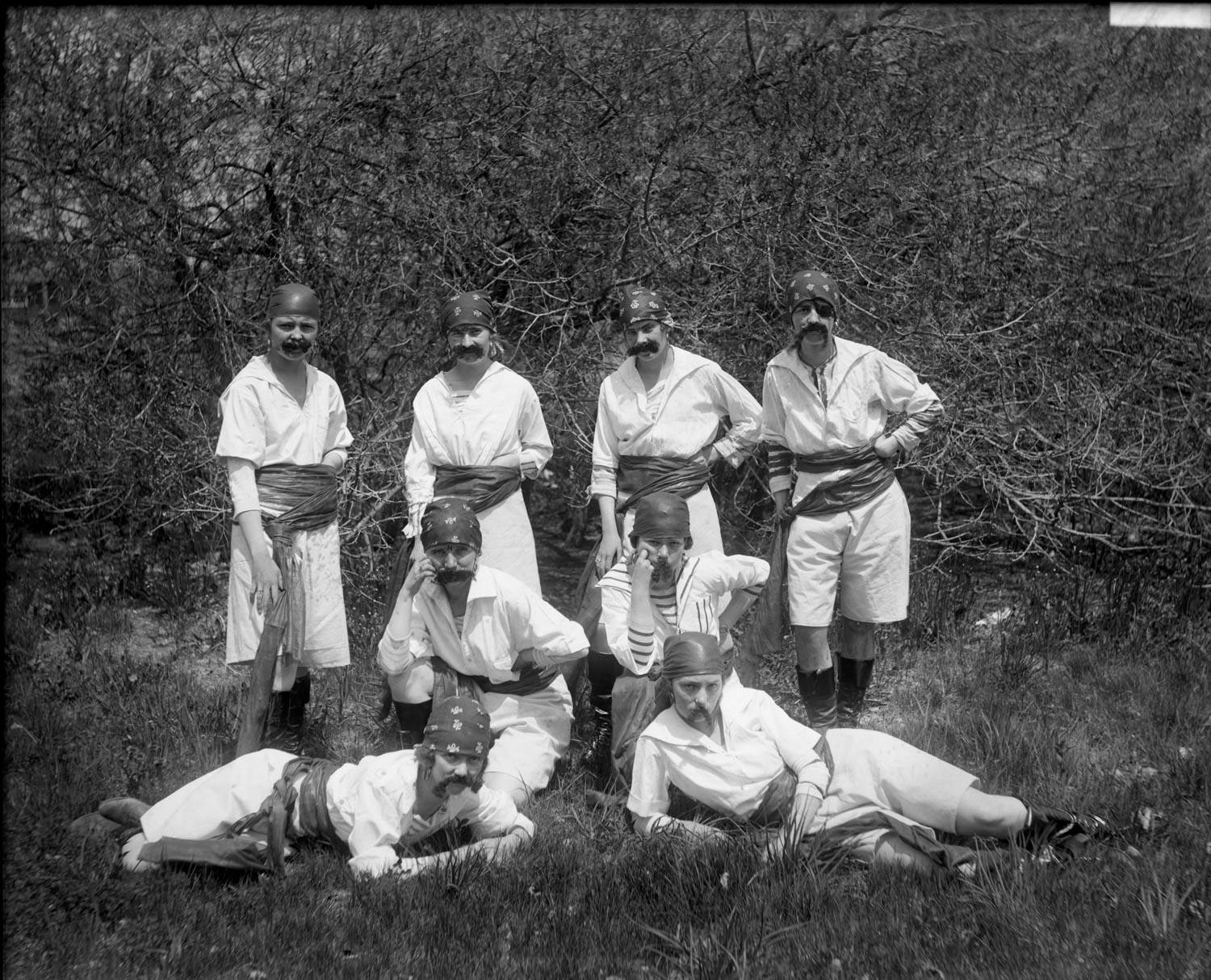 A group of eight individuals posing in a nature scene, dressed as pirates.