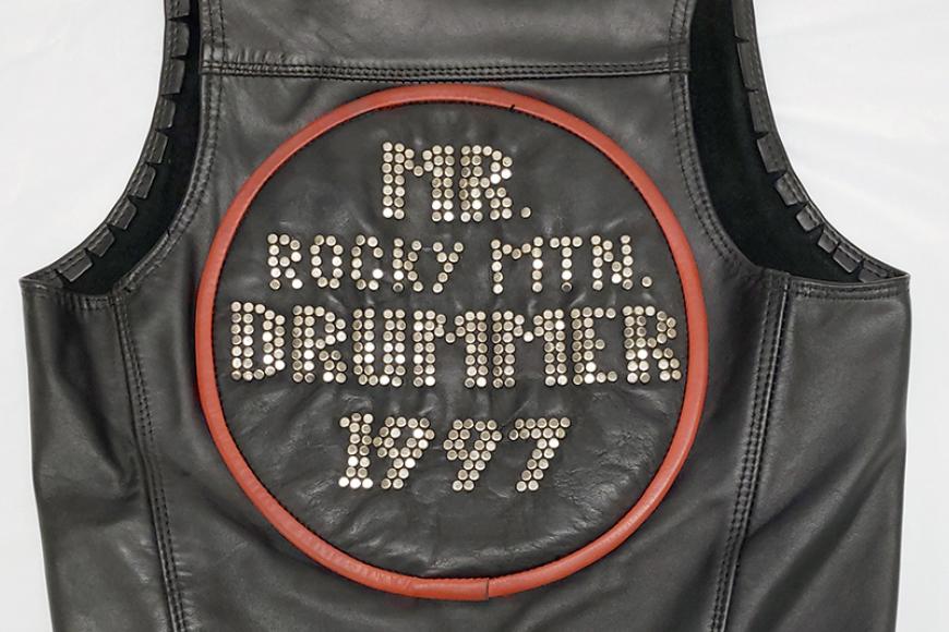 A leather vest, with words on the back in rhinestones: "Mr Rocky Mtn Drummer, 1997." [sic]