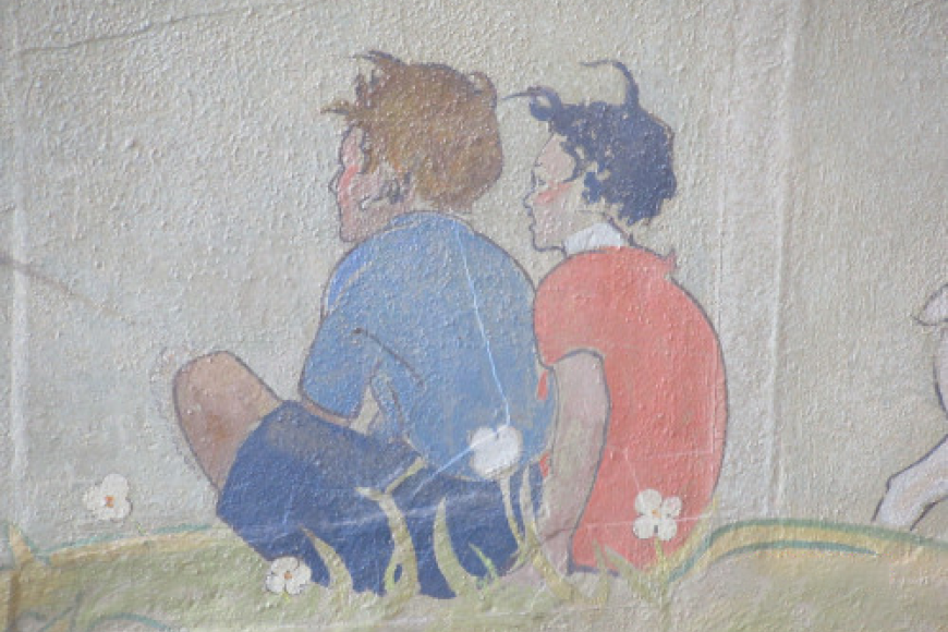 A mural painting of two boys sitting in a flower field. They wear blue and red.
