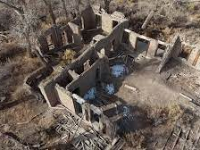 Photo of the ruins of a multi-room building, which now has no roof and the walls are exposed to the elements. This is an aerial view of the building site.