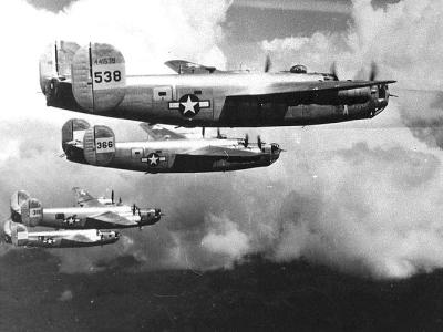 A squadron of four World War 2 era bomber planes flying in formation.
