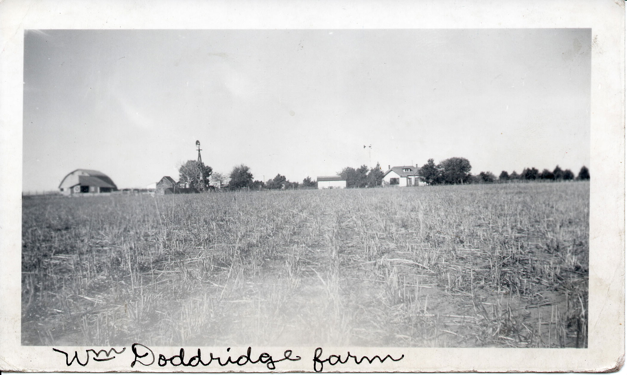 An historic photograph looking across a field towards the Glenn Doddridge Farm & Ranch.