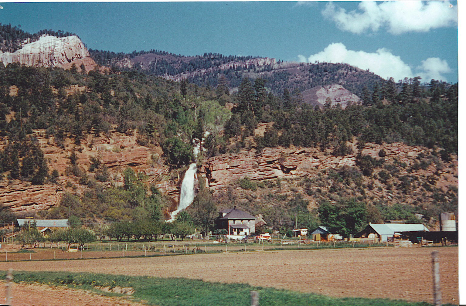 A far shot of the Waterfall Ranch, including the waterfall for which the ranch is named and the original home..