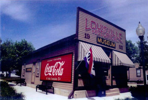 A picture of the building with a large sign on the facade, two awnings beneath, a flag coming out, and on the side is a large Coca-Cola sign.