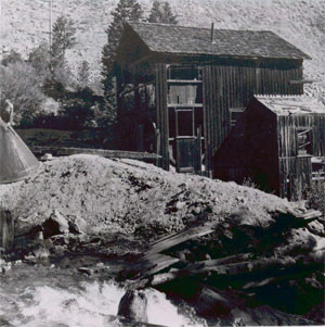 A historic photo of some rocks in the foreground with a building behind.