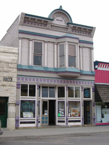 A photo of the building with bay window on the second floor above the shopfront. 
