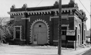 A black and white photo of the dark station from a slight angle and elaborate white trim and phone pole in front. 