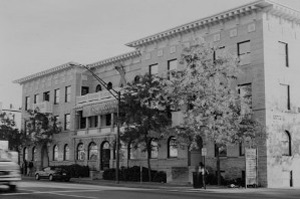 A black and white photo of the apartment building with a few trees on either side of it.