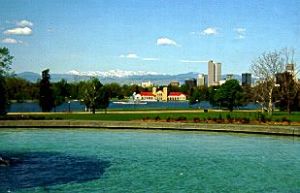A view of the City Park pavilion with mountains in the background and lake in the foreground.