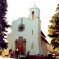 A view of the chapel with two large pine trees on either side. 