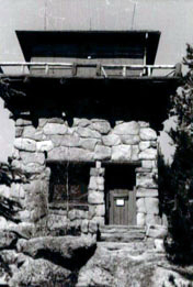 A black and white photo of the lookout with large stone walls and a platform under an overhanging roof.