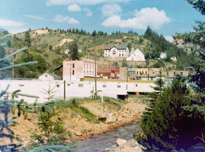 A view of some of the buildings over a river and before some hills in the background. 
