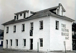 A photo of the building with white walls and prominent sign written on the side and hipped roof. 