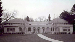 A black and white view of the hall with hipped roofs at either end and an arcade in the center. 