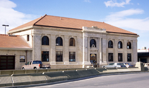A picture of the depot with hipped roof and arched windows over straight ones below. In the center is a large ornate entrance. 