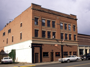 A view of the building from the corner with red brick walls and windows on the front. 