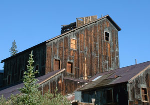 A photo of the mill with tall pitched roofs and wooden side panels. 