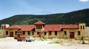 A photo of the school with pitched red roof and mountains in back. 