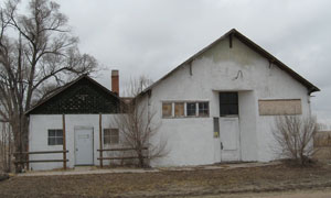 A view of the building with double gabled roofs. On the left stands a leafless tree. 