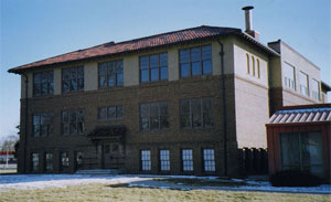A picture of the high school with snow in the foreground and hipped roof.