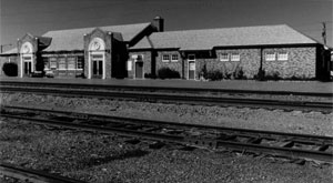 A black and white photo of the depot with tracks in front. 
