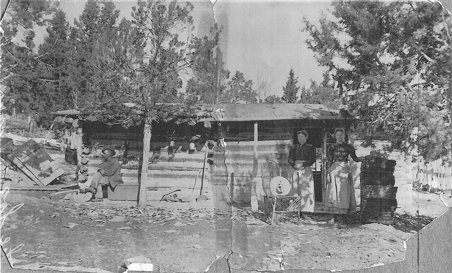 Historic image showing the original log cabin, torn down in the early 1900s.  Elsie Harris is on the right. 