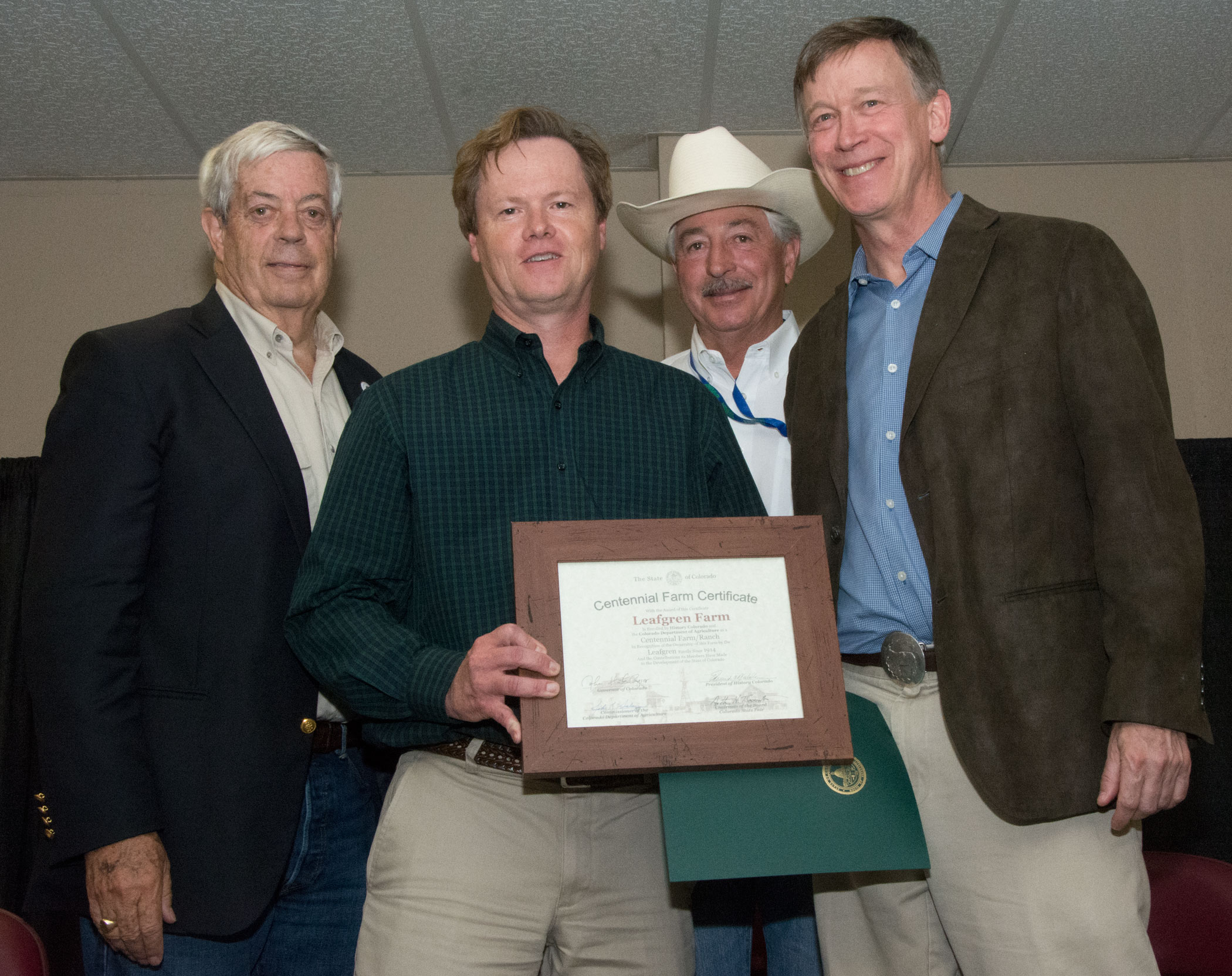 One of the Leafgrens receiving the Centennial Farm award on stage from Ed Nichols, John Salazar and John Hickenlooper.