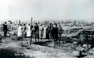A black and white photo of the site around the time of the event with a group of people standing in the center of the pictures.