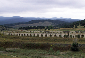 A view of the district with arched railroad  before some mountains and in front of some mountains. 