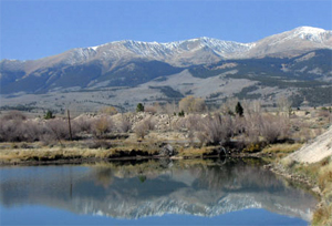 A view of a lake on the camping reflecting the brush and mountains above.