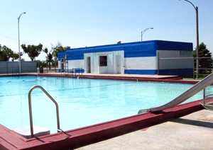 A view of the pool with blue and white building behind it.
