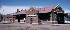 A photo of the depot with brick walls and gable roof with a cross gable section in the center.